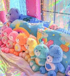 there are many stuffed animals sitting on the bed with colorful sheets and curtains behind them