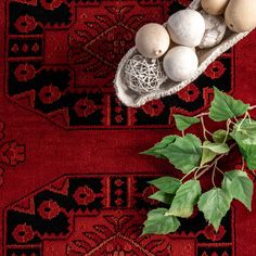 mushrooms are in a bowl on top of a red rug next to a green plant