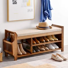 a wooden bench with shoes on it next to a hat rack and coat hanger