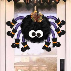 a halloween decoration with a spider on the front door and happy hallows hanging from it's side