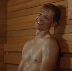 a man is smiling while sitting in the sauna