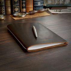 a leather notebook with a pen on top of it