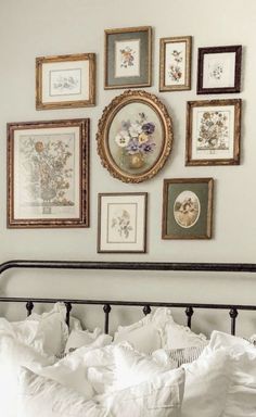 a bed with white sheets and pictures on the wall above it, along with pillows