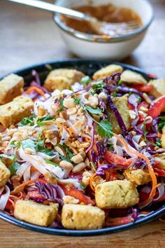 a salad with tofu, carrots, red cabbage and peanuts in a bowl