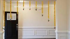 an empty room with white walls and yellow garlands hanging from the ceiling over the door