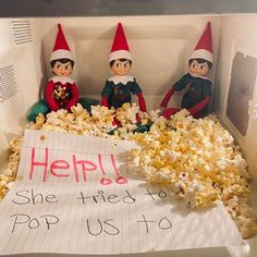 two elfs sitting in a box with popcorn and a sign that says help she tried to pop us to