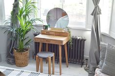 a bedroom with a mirror, stool and plant in the corner on the floor next to it