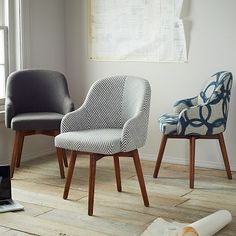 three different chairs in front of a window, one is blue and the other is white