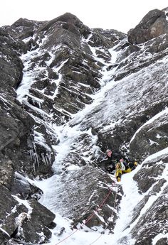 a man climbing up the side of a snow covered mountain