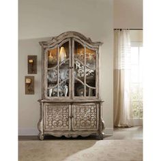 an ornate china cabinet with glass doors and carvings on the front, in a living room