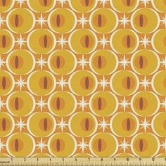 an orange and yellow fabric with circles on the side, in front of a ruler