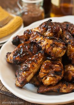 grilled chicken wings on a white plate with mustard and seasoning in the background