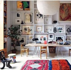 a living room filled with furniture and pictures on the wall next to a table covered in books