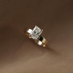 an engagement ring with a princess cut diamond in the center on a brown background,