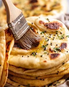 there is a brush that is on top of some flatbreads with cheese and seasoning