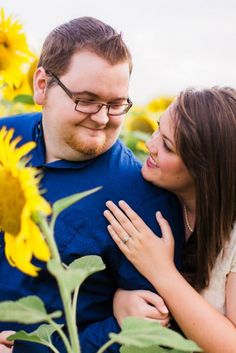 a man and woman are hugging in the sunflower field