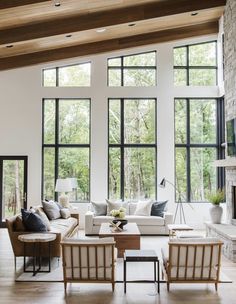 a living room filled with lots of furniture next to a fire place and large windows