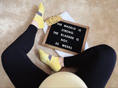 a woman sitting on the floor with her feet up next to a sign that says, the waddle is the bladder is not 35 weeks