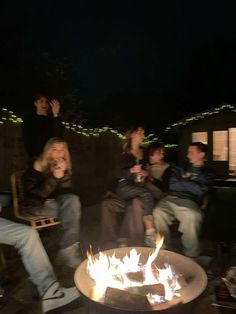 people sitting around a fire pit at night