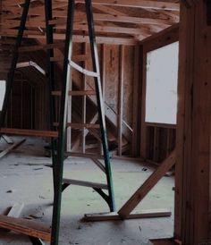 an unfinished room with wooden framing and ladders