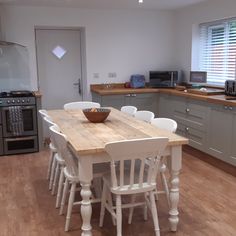 a kitchen table with chairs and a bowl on it in front of the stove top