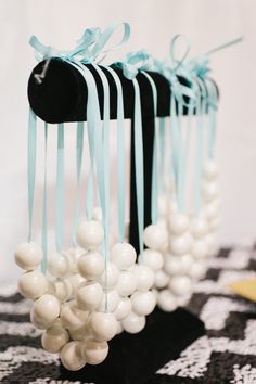 some white balls are tied to black and white material with blue ribbons on them, along with other beads