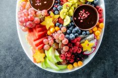 a white plate topped with lots of fruit and chocolate dips on top of it