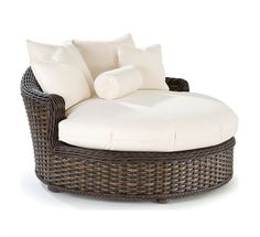 an outdoor wicker lounge chair with white cushions and pillows on the back, in front of a white background