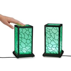 a hand is touching the top of two small lamps that have broken glass on them