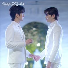 two men in white suits standing next to each other with their hands on one another