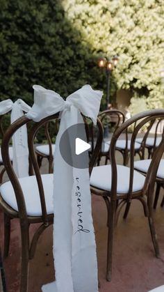 there are many chairs that have been decorated with white ribbons and bows on the back