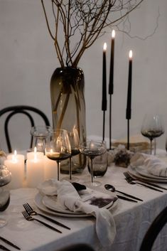 a table set with candles, plates and napkins