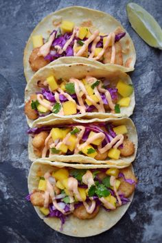 three fish tacos with mango slaw and cilantro sauce on the side