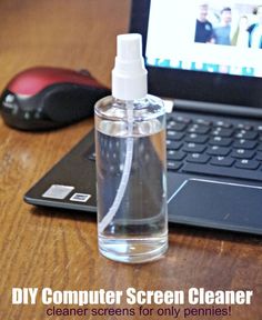 a laptop computer sitting on top of a wooden desk next to a bottle of cleaner