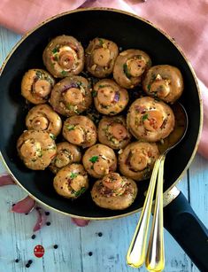 a pan filled with cooked mushrooms on top of a table next to utensils