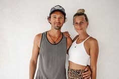 a man and woman standing next to each other in front of a white wall smiling