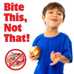 a young boy holding an apple in front of a sign that says bite this, not that