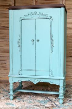 an old blue cabinet with ornate carvings on the front and sides, painted aqua green