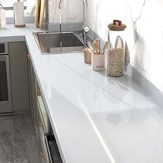 a white counter top in a kitchen next to a stove and sink with utensils on it