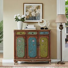 an ornately decorated sideboard with flowers and plants on it in a living room