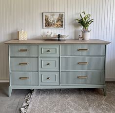 an old dresser is painted blue and has gold pulls on the drawers, along with a potted plant