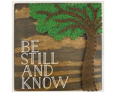 a wooden sign that says be still and know with a tree on top of it