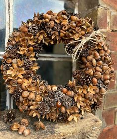 a wreath made out of pine cones and acorns on a window sill