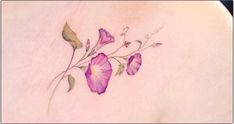 a pink flower tattoo on the back of a woman's shoulder