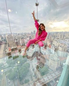 a woman in pink shirt and pants standing on top of a glass floored building