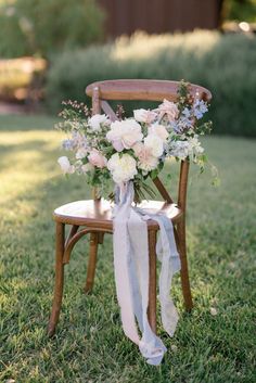 a bouquet of flowers is sitting on an old wooden chair in the middle of grass