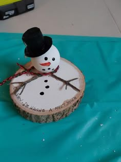 a snowman is sitting on top of a piece of wood