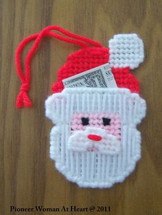 a knitted santa clause ornament with money sticking out of it's mouth