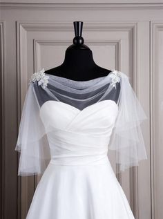 a white wedding dress on a mannequin stand with veils over the shoulders