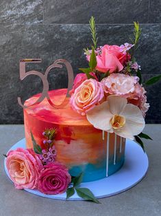 a colorful cake with flowers and the number 50 on it is sitting on a plate